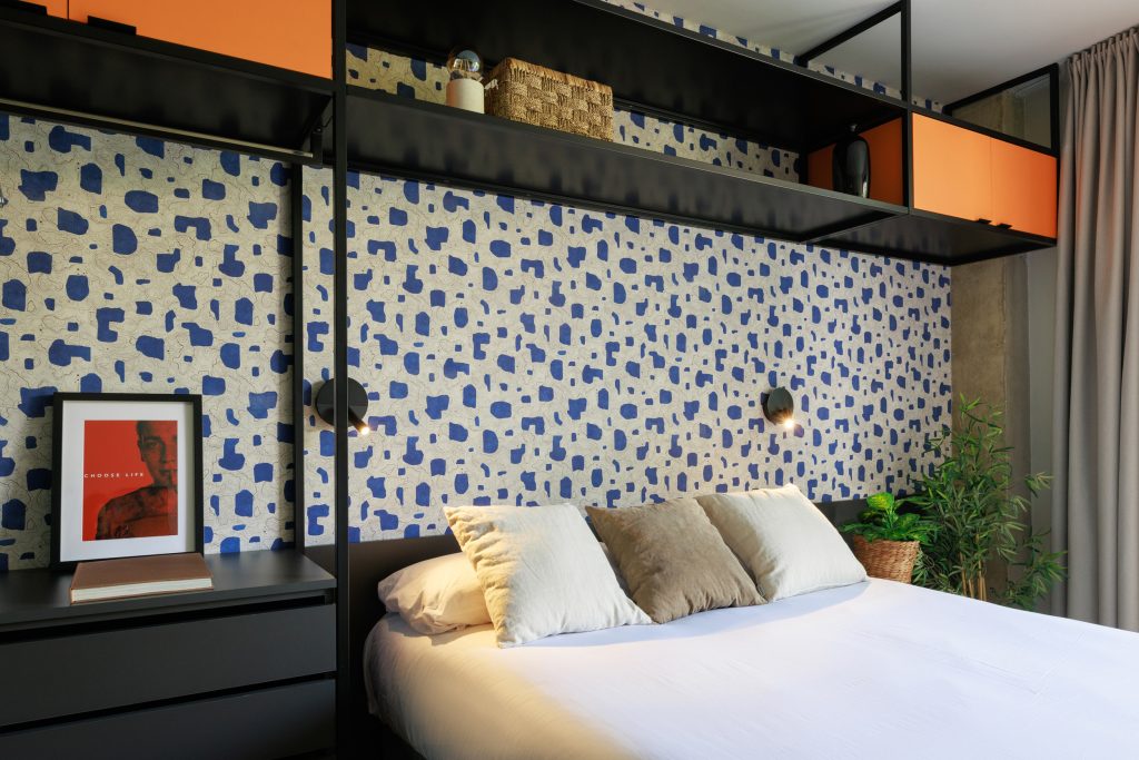 Patterned headboard and black metal shelving in a Gavà apartment.