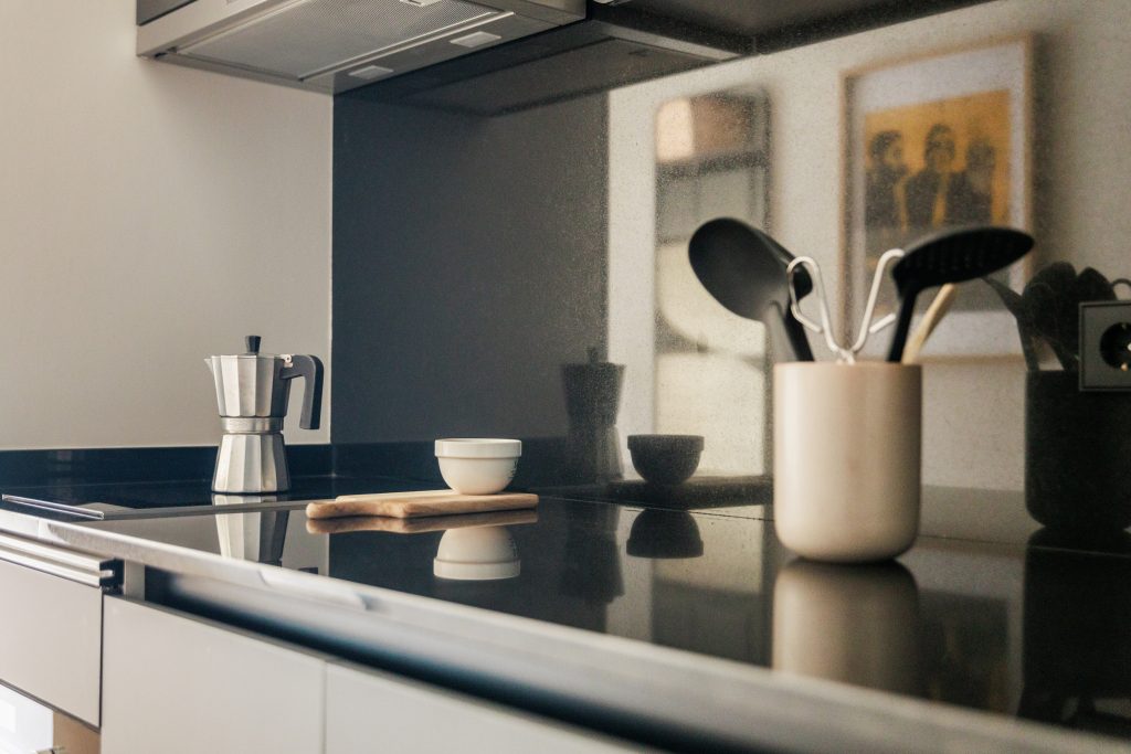 Private Gavà kitchen with dark cabinets, utensils and a moka pot.