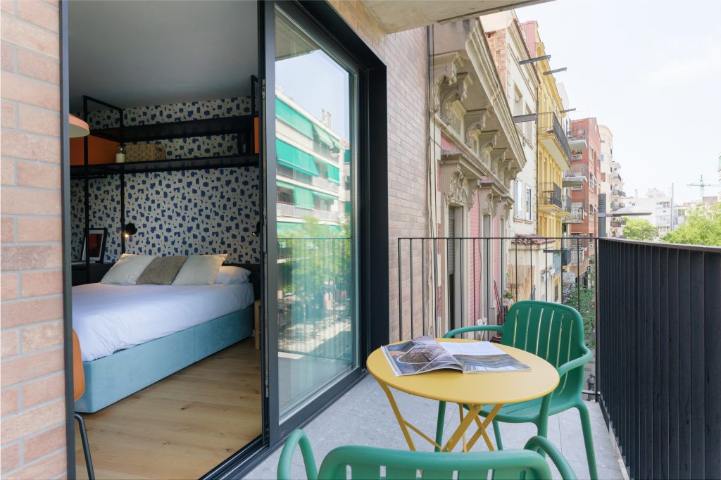 Private balcony at Gavà with a yellow table, green chairs and a view along the street.