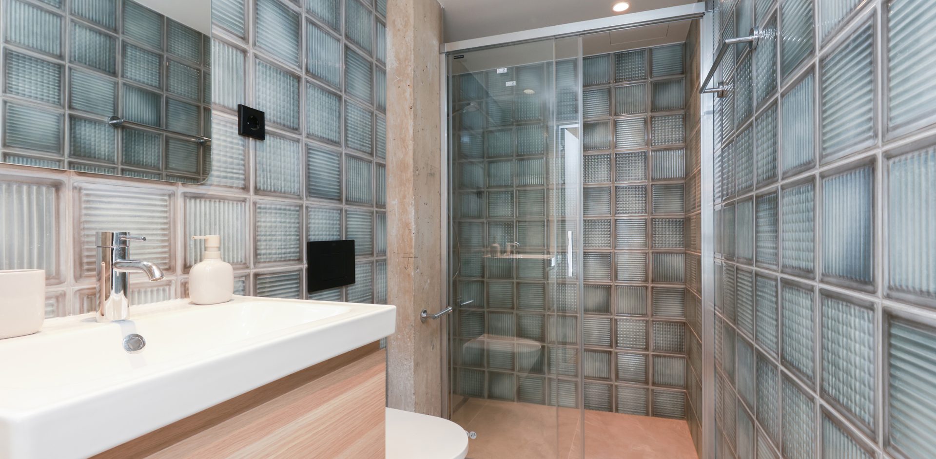 Private Gavà bathroom with a glass-block shower enclosure and wood-tone vanity.
