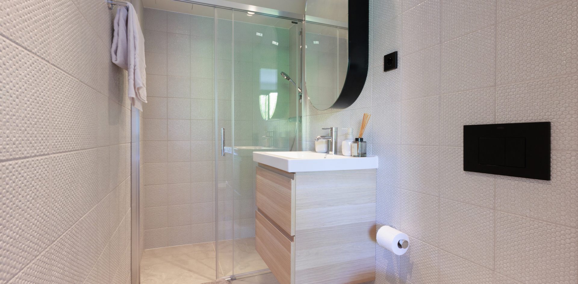 Gavà bathroom with a shower, basin and oval mirror.